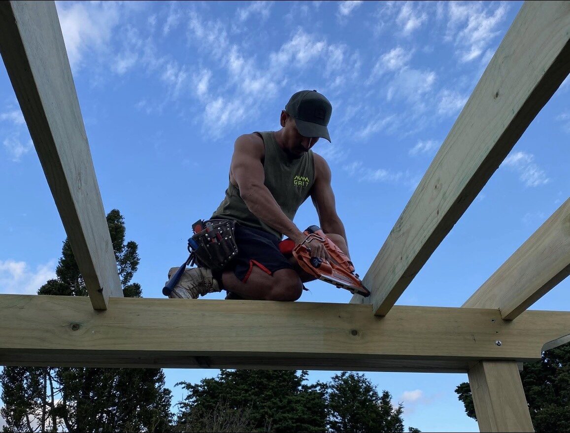 GRIT carpenter cutting rafters while constructing a timber pergola