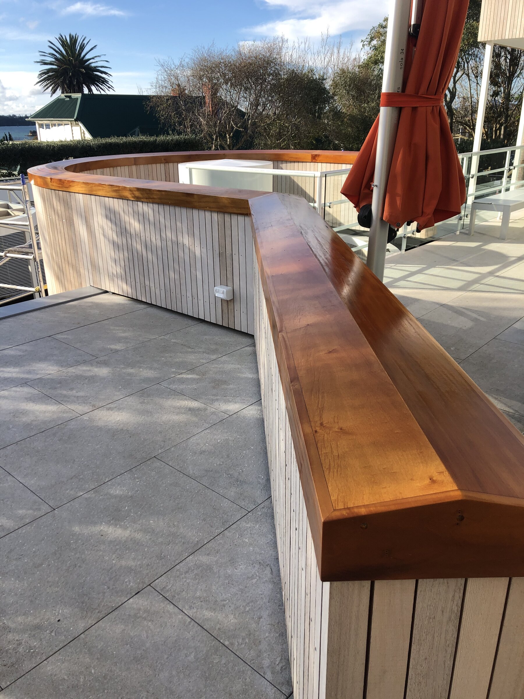 Curved outdoor bench with hardwood capping and vertical timber cladding