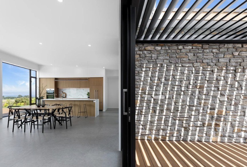 Connection between the indoor dining area and louvred pergola courtyard with Lake Taupō views
