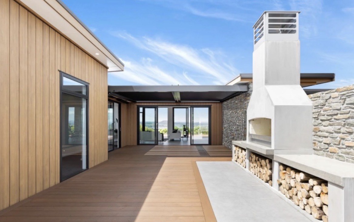 Penny Homes outdoor courtyard with motorised pergola, stone wall and fireplace